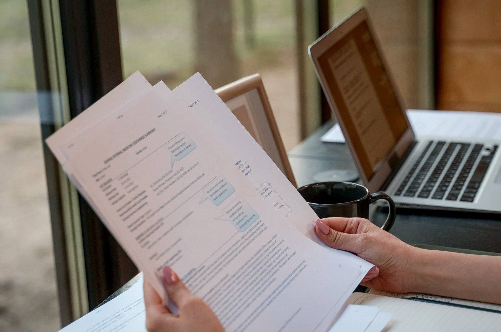 Reviewing printed documents beside a laptop and coffee