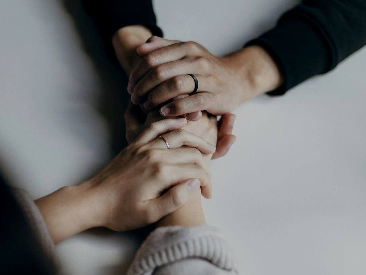 Two people holding another's hands in a gesture of support